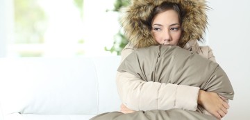 Eine Frau sitzt unter einer Decke in einer Winterjacke