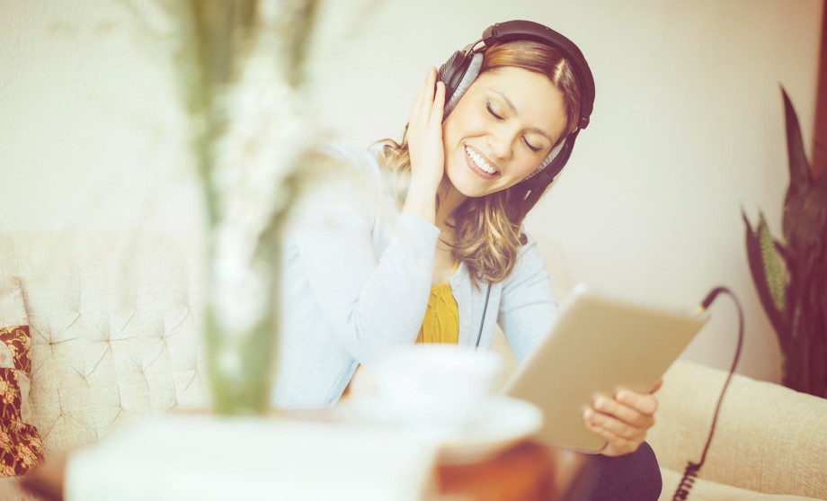 Strompreis: eine Frau hört Musik über Kopfhörer von einem Tablet