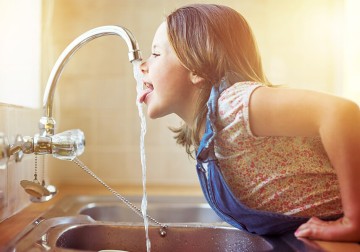 Wasser: ein Mädchen trinkt Wasser aus dem Wasserhahn
