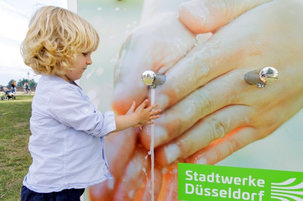 Kind wäscht sich die Hände am Händewaschtower.