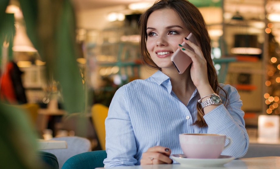 Rückruf vereinbaren: Eine Dame mit einer Tasse Kaffee telefoniert mit Ihrem Handy