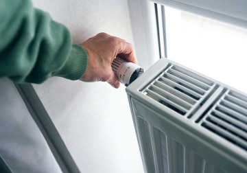 Eine Frau erhöht oder senkt die Temperatur am Heizkörper in der Wohnung. © Ekaterina Goncharova / Moment via Getty Images