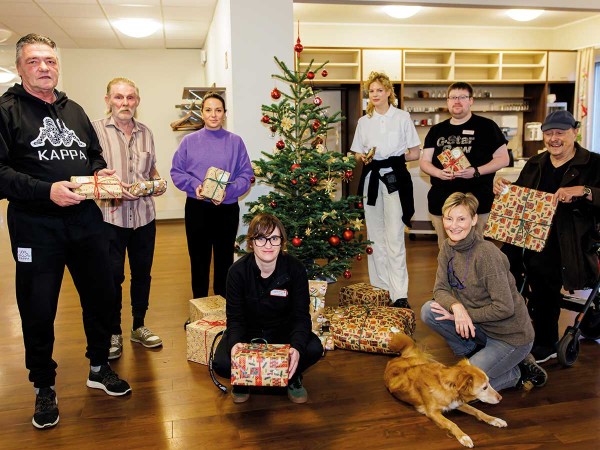 Glückliche Beschenkte präsentieren ihre Geschenke vor dem Weihnachtsbaum
