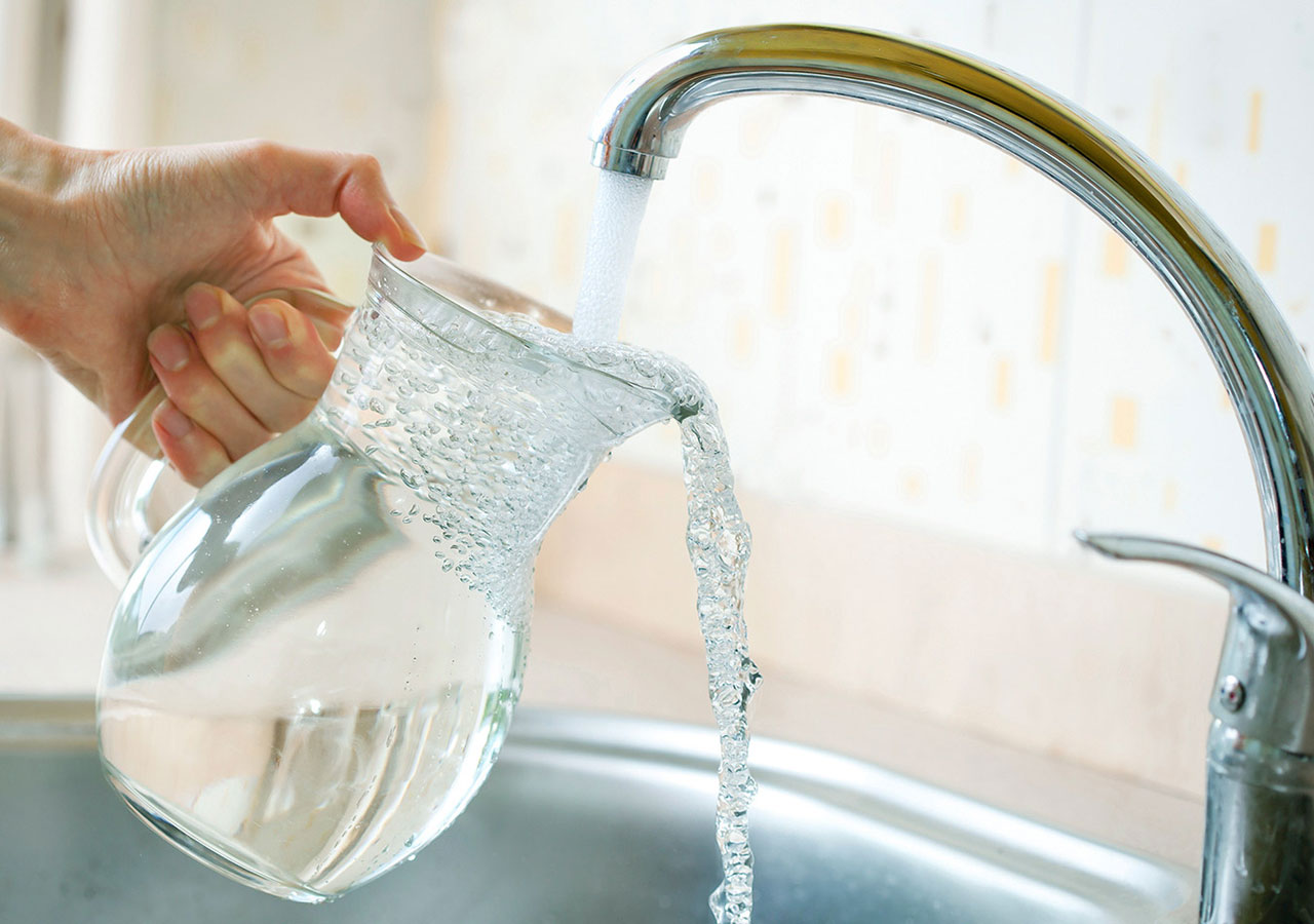 Ein Glaskrug wird mit erfrischendem Trinkwasser gefüllt