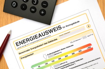 Energieausweis für Wohngebäude mit Kuli und Taschenrechner