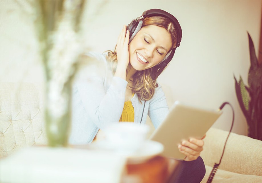 Strompreis: eine Frau hört Musik über Kopfhörer von einem Tablet