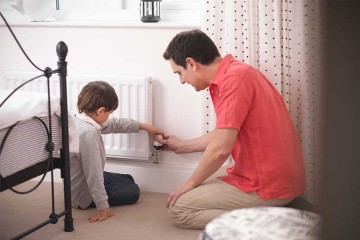 Vater dreht mit seinem Sohn Heizung runter © Klaus Vedfelt / DigitalVision via Getty Images