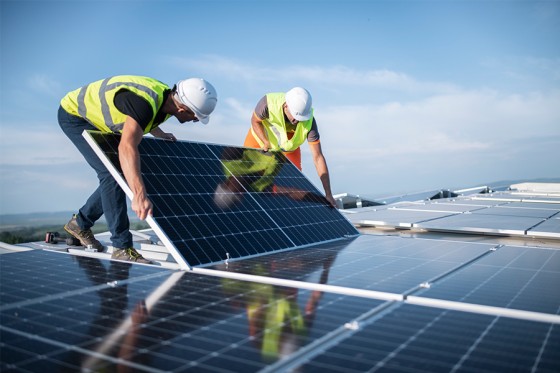 Zwei Ingenieure installieren eine Photovoltaikanlage auf einem Dach.