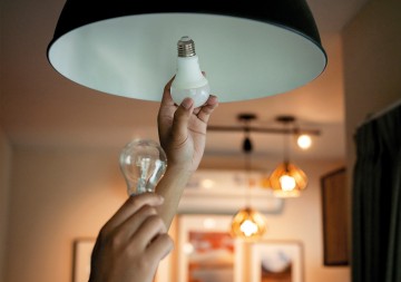 Eine Glühbirne wird gegen eine energiesparende LED-Lampe ausgetauscht. © Thana Prasongsin / Moment via Getty Images 