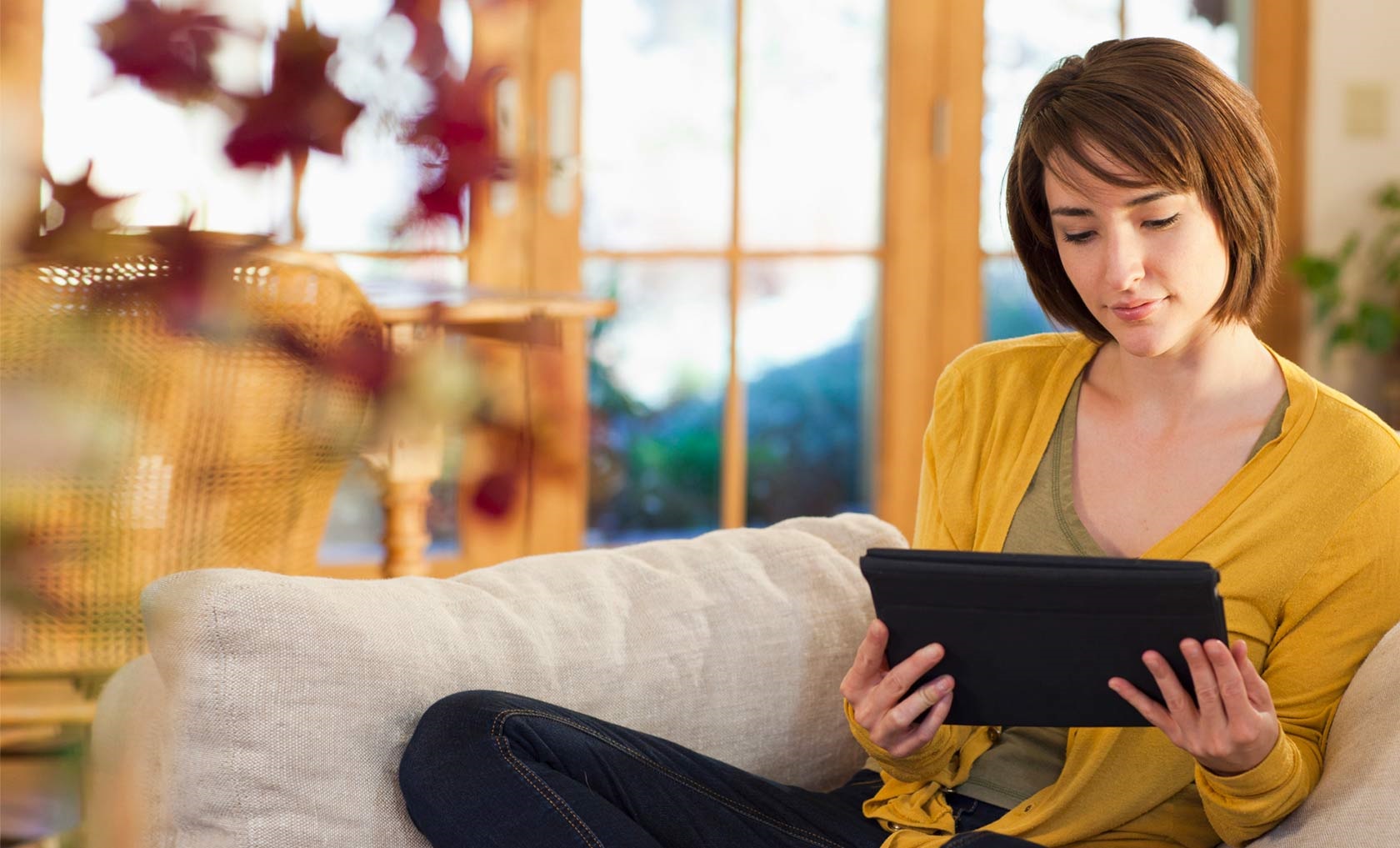 Kündigen: Eine Frau sitzt auf der Couch und liest was auf dem Tablet