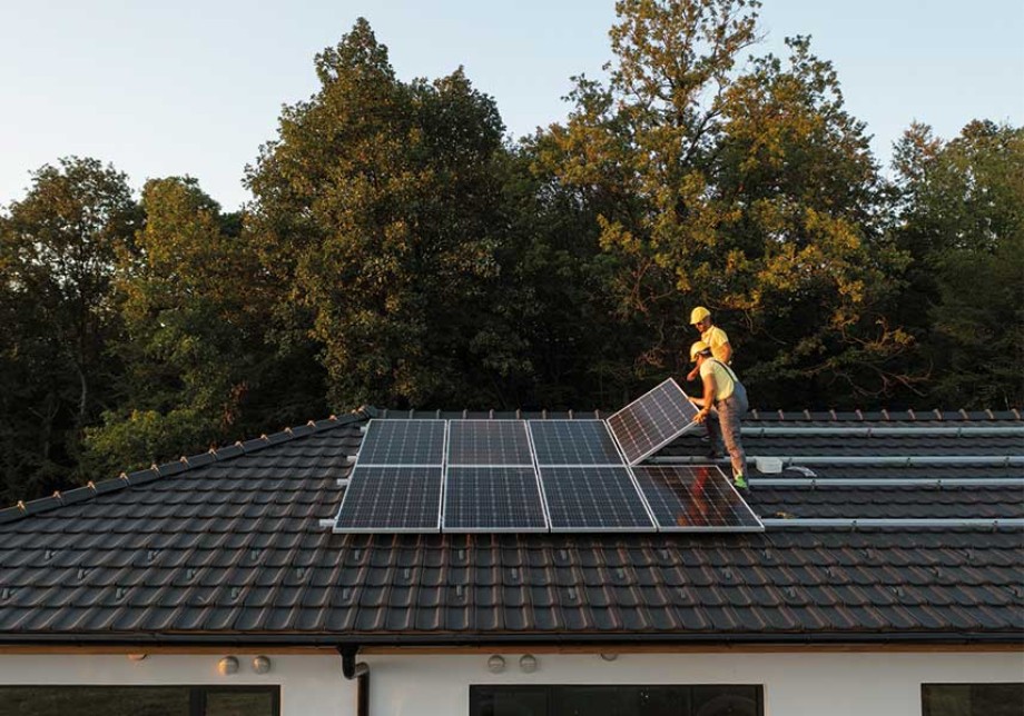 Zwei Arbeiter installieren Sonnenkollektoren auf dem Dach eines Hauses. © ArtistGNDphotography / E+ via Getty Images