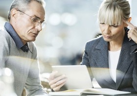 Kontakt Geschäftskunde: zwei Personen sitzen am Tisch und schauen auf ein Tablet