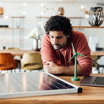 EnergieBusiness: Mann schaut auf ein Solarpanel
