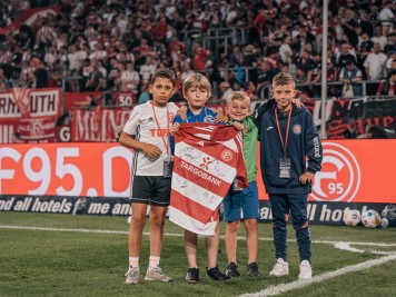 Vier Kinder präsentieren ein unterschriebenes Fortuna Düsseldorf Trikot