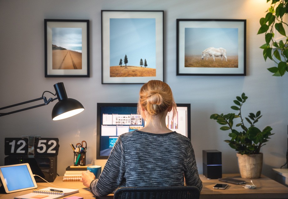 Energiesparen im Homeoffice: Eine Frau sitzt an ihren Schreibtisch vor einem Bildschirm, der seitlich mit wärmendem Lichtstrahl beleuchtet wird. 
