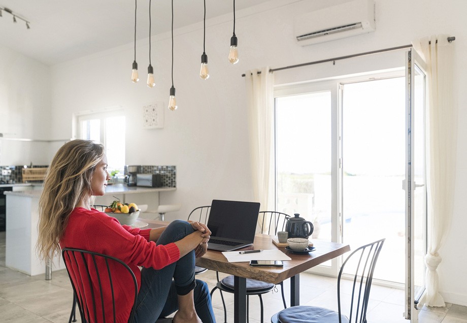 Energiesparen im Homeoffice: Eine Frau genießt ihre Pause vor einem ausgeschalteten Laptop.