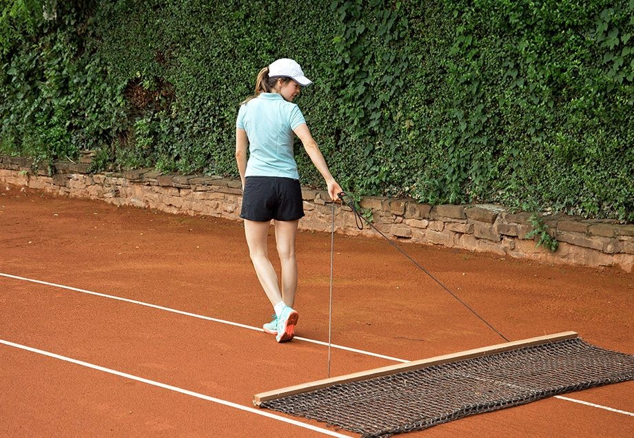 Denise, wie sie den Tennisplatz mit dem Schleppnetz abzieht.