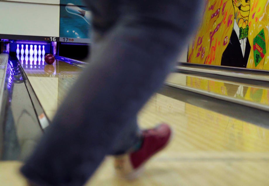 Eine verschwommene Aufnahme zweier Beine in Bewegung am Anfang einer Bowlingbahn. 