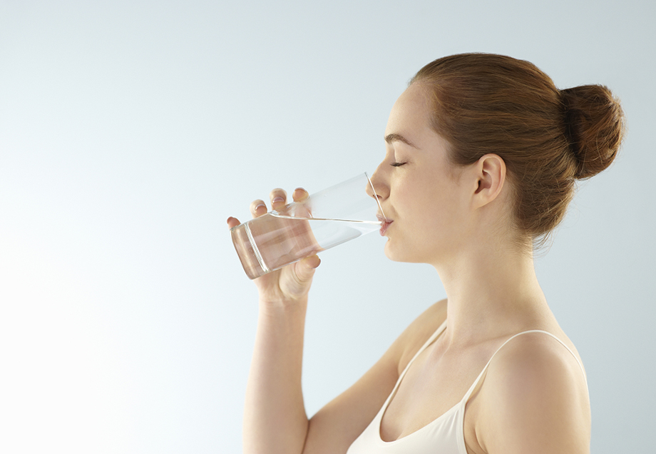 Eine Frau trinkt ihr kühles Glas Wasser. 