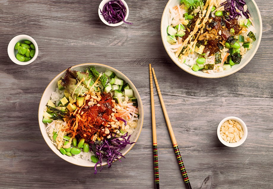 Zwei Salad Bowls mit Reis und Avocado. Zwischen den Schalen liegen Essstäbchen.