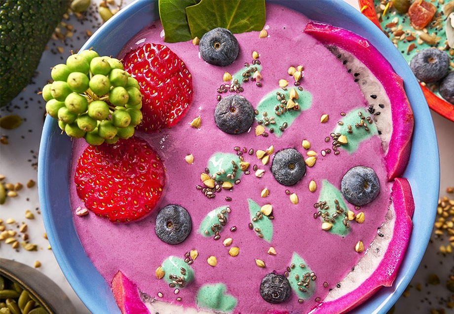 Eine Frühstücksbowl gefüllt mit pürierten Acaibeeren, Toppings wie frischen Früchten, Kokosflocken, Knuspermüsli und Chiasamen.