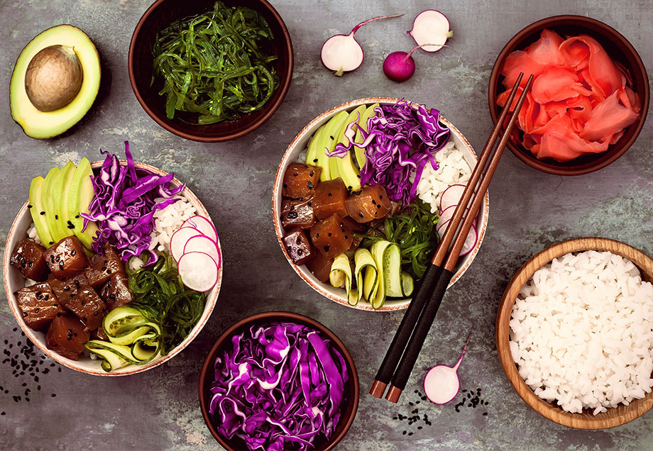 Zwei Poke Bowls – umgeben von den einzelnen Bestandteilen der Bowls.