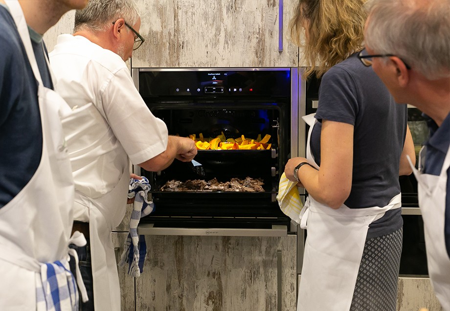 Schüler der Kochschule Düsseldorf stehen vor dem geöffneten Ofen.