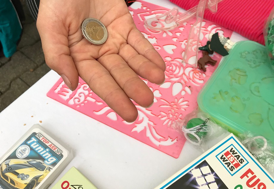 Hand mit einem 2-Euro-Stück auf der Handfläche.