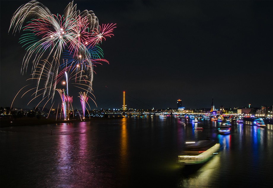 In bunten Farben explodierendes Feuerwerk über dem nächtlichen Rhein in Düsseldorf.