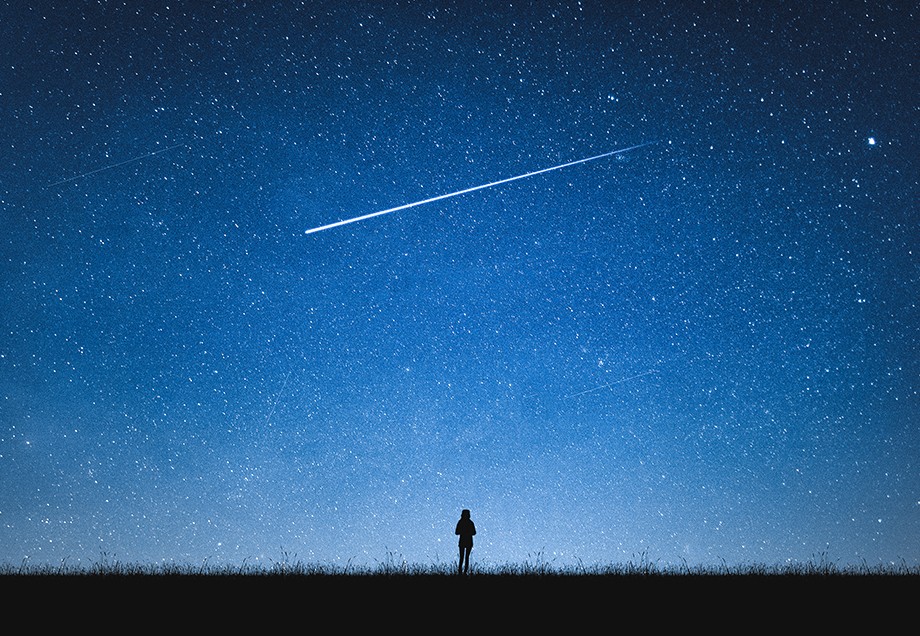 Eine einzelne Person unter einem Nachthimmel voller Sterne.