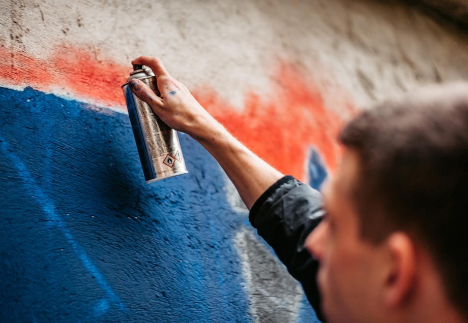 Ein Mann besprüht eine Wand mit einer Spraydose. 