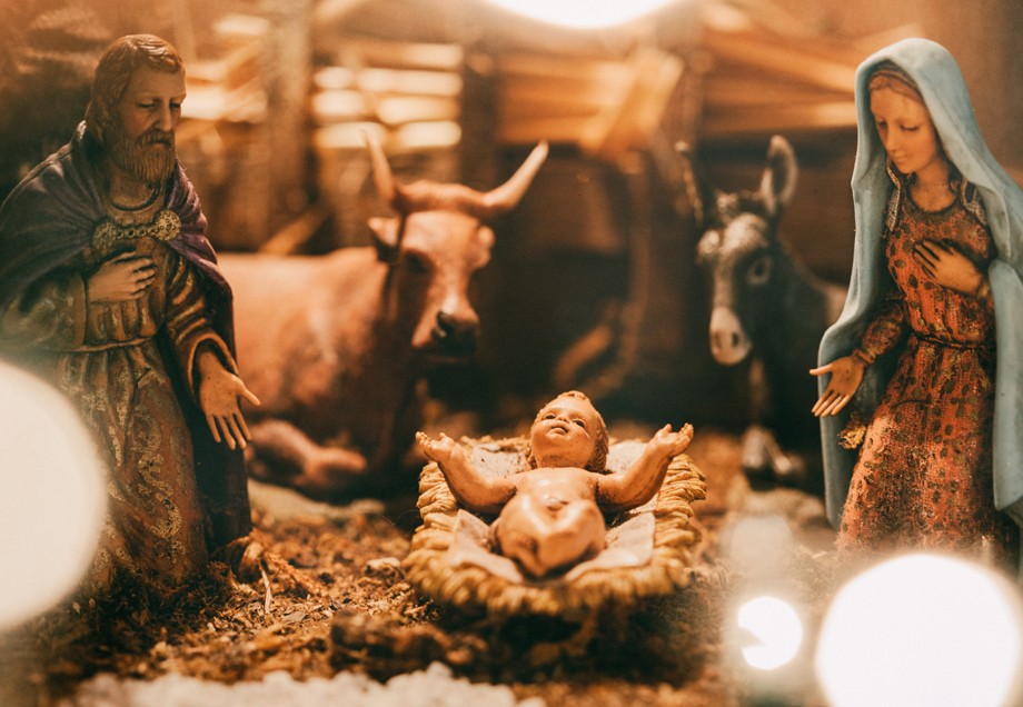Krippenfiguren aus Holz in Nahaufnahme – Josef, Maria, Jesus mit Ochse und Esel im Hintergrund