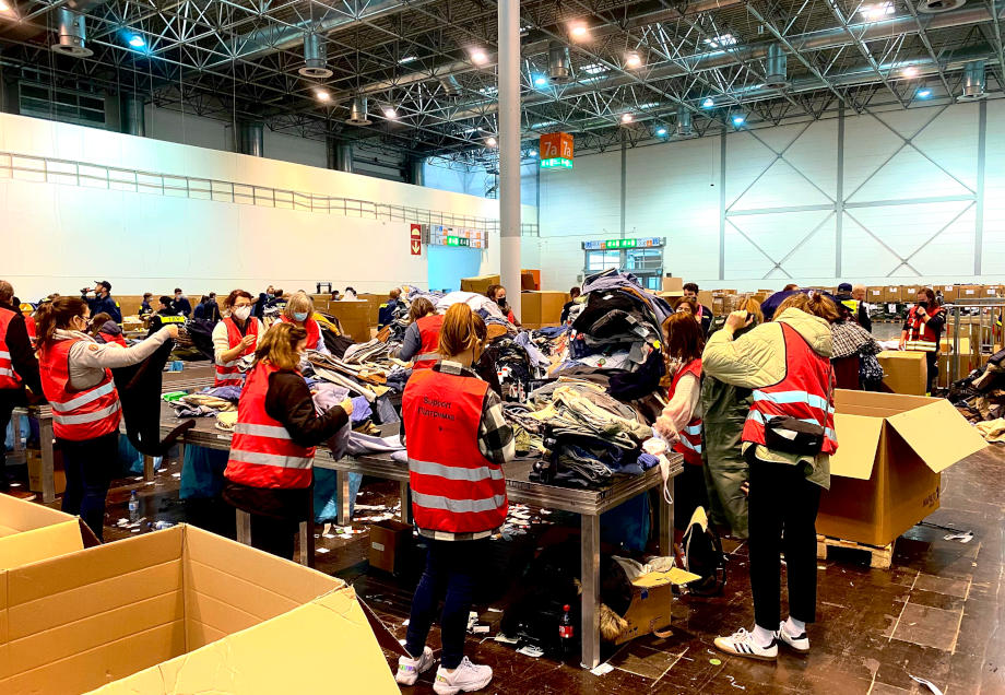 Helfer:innen unterstützen beim Sortieren und Verpacken von Sachspenden in einer Düsseldorfer Messehalle. © Andreas Vogt