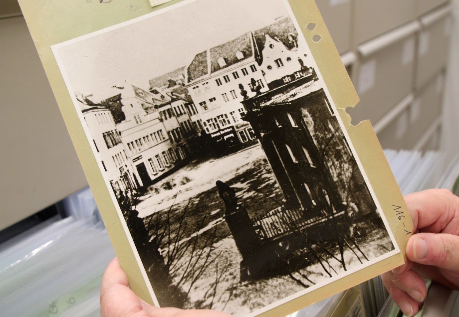 Mitarbeiterin hält ein historisches Foto, das im Stadtarchiv Düsseldorf verwahrt wird.