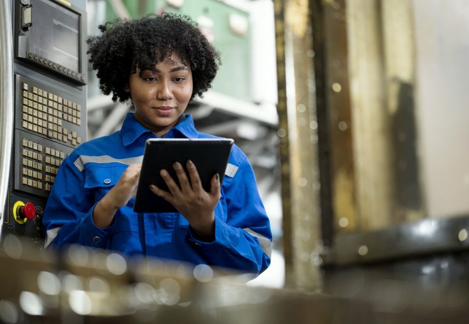Eine Frau bedient ein Tablet zur Steuerung verschiedener Maschinen in einer großen Produktionsstätte.