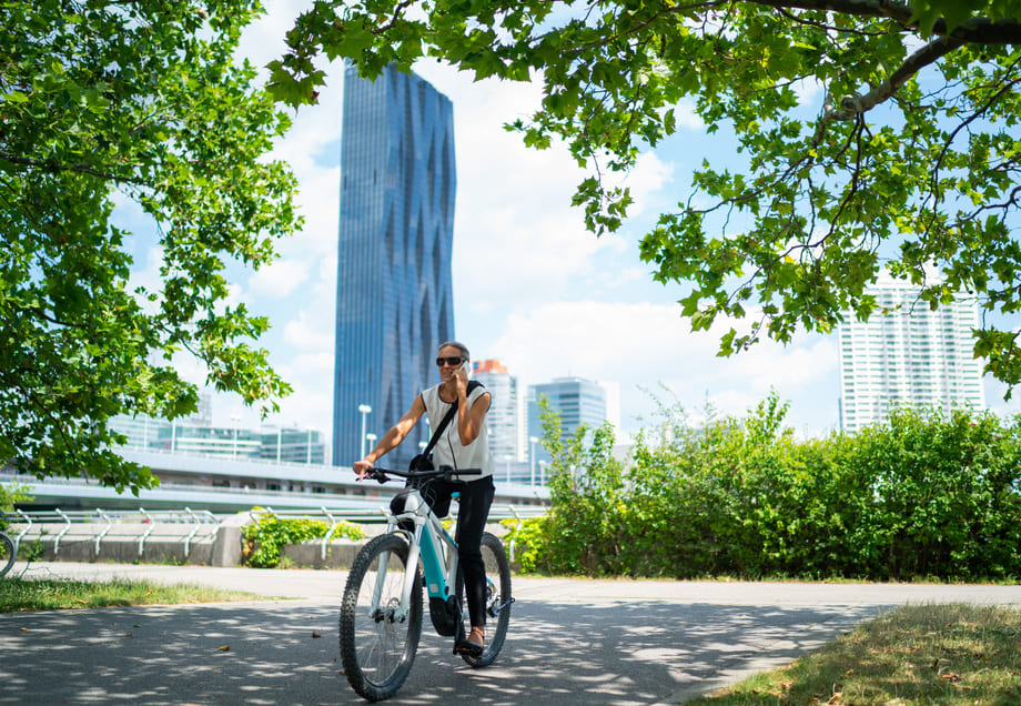 Klimaneutralität: Eine Frau fährt auf ihrem Fahrrad durch einen grünen Park.