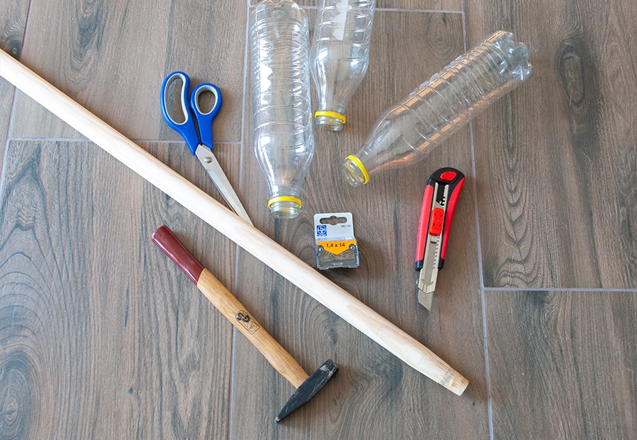 So baut man einen Besen: Holzstab, Plastikflaschen, kleine Nägel und stabiles Klebeband. Dazu Schere, Hammer und Teppichmesser.