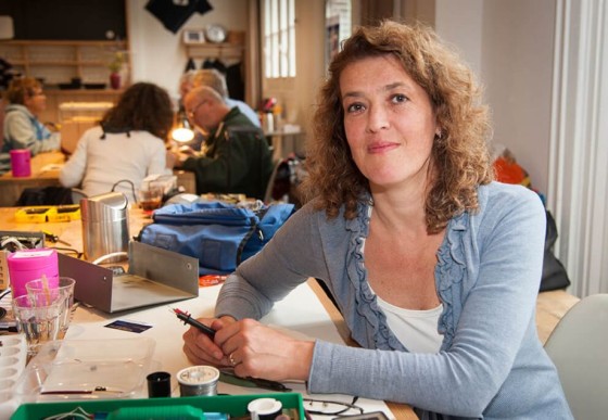 Martine Postma, die Gründerin der Initiative für Repair Cafés, sitzt an einem Arbeitsplatz mit Werkzeug.