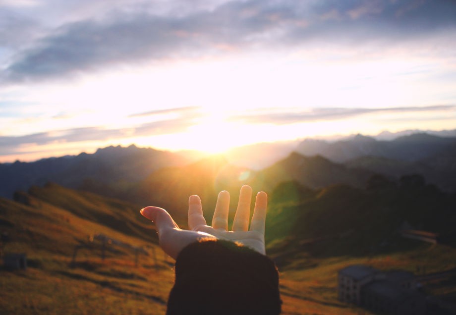 Eine ausgestreckte Hand, die nach der Sonne greift