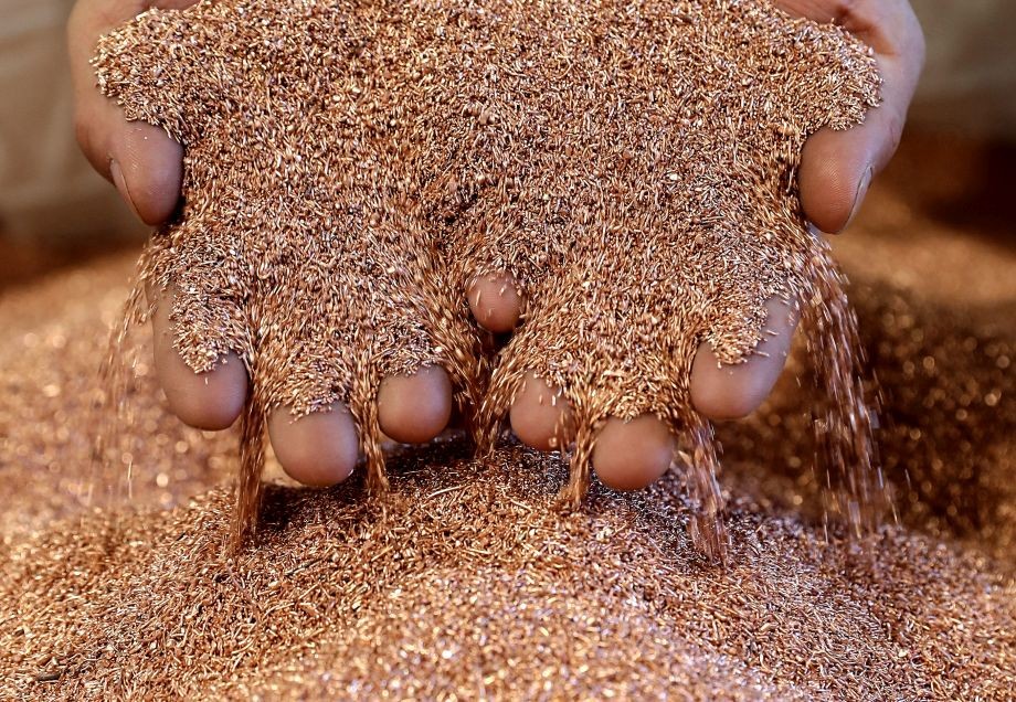 Hände halten Kupfergranulat aus recyceltem Kupfer. 