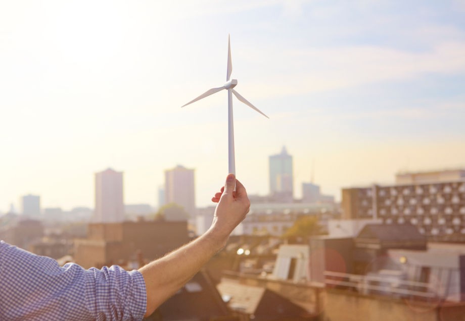 Eine männliche Hand hält eine Modell-Windkraftanlage. © Ezra Bailey / Stone via Getty Images 