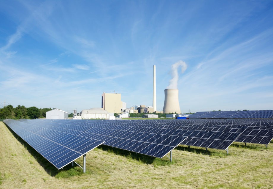 Eine Photovoltaikanlage mit Kohlekraftwerk im Hintergrund