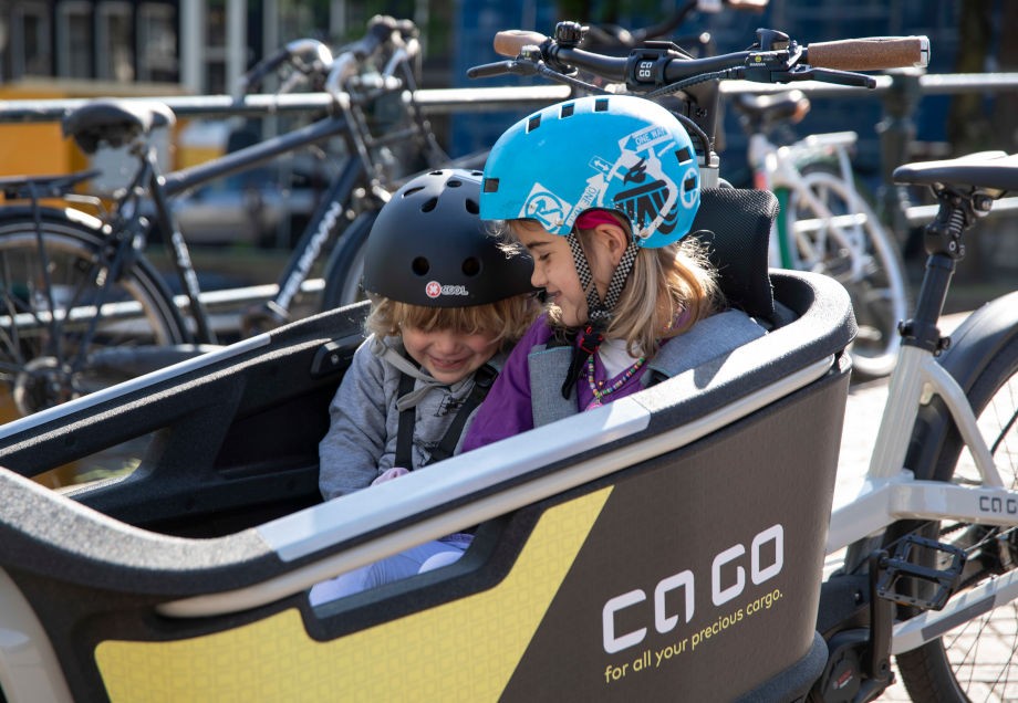 Kinder mit Helm sitzen im E-Lastenrad
