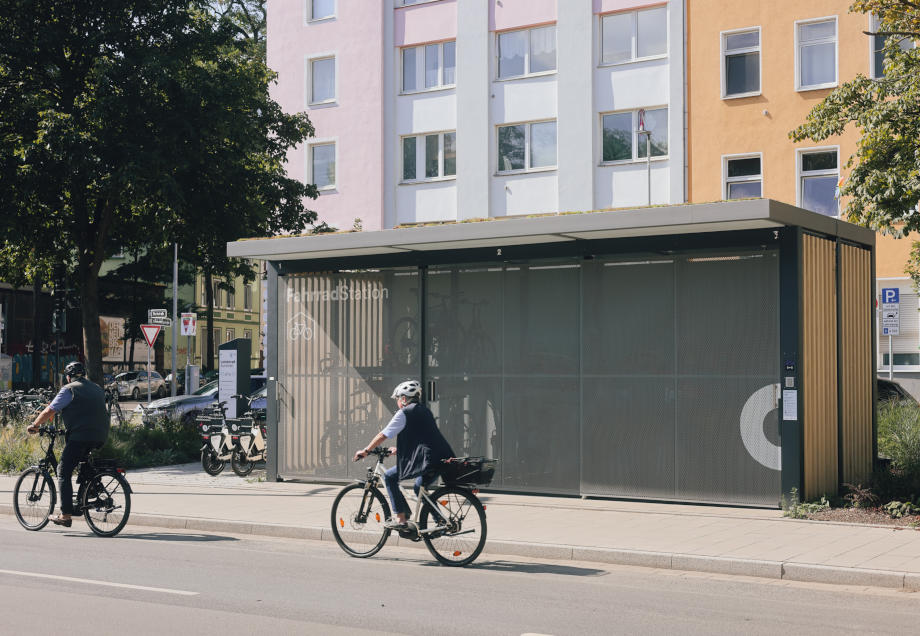 Zwei Radfahrer:innen passieren die Mobilitätsstation am Bachplätzchen in Düsseldorf. © Connected Mobility Düsseldorf GmbH