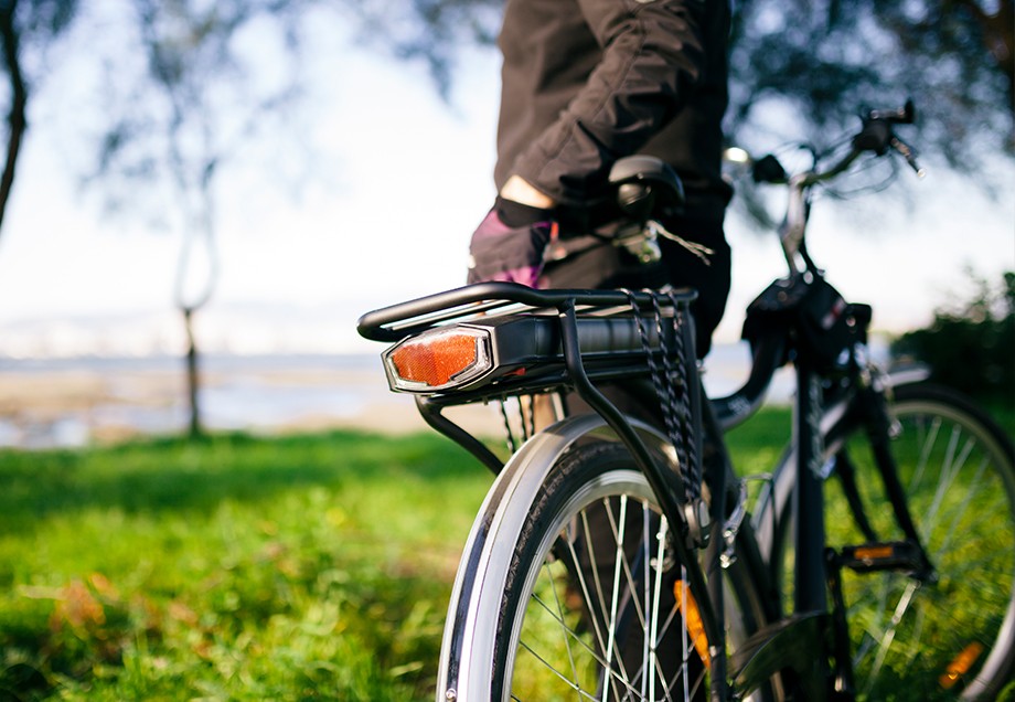 Ein Radfahrer steht mit seinem Fahrrad in der Natur und schaut auf das Wasser.