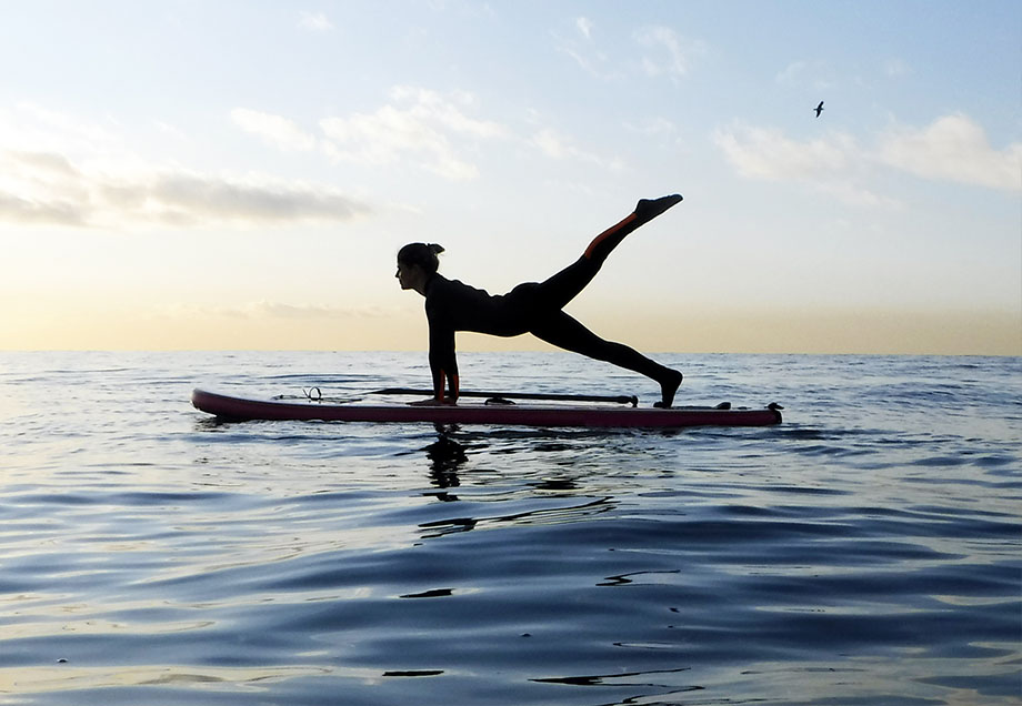 Frau in einer Yogapose auf einem Surfbrett