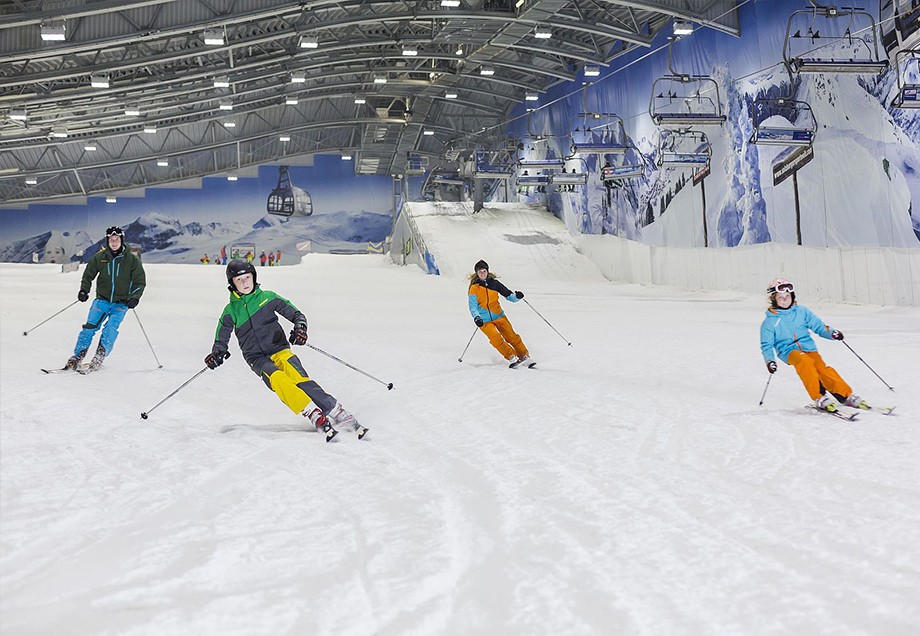 Vier Skifahrer wedeln die perfekt präparierte Skipiste in der Skihalle Neuss herunter.