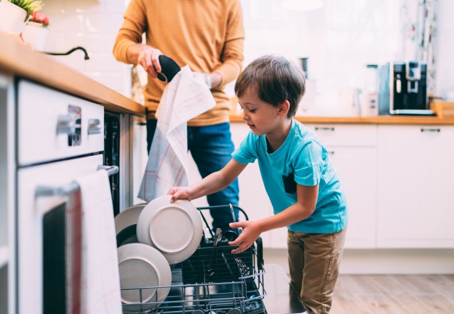 Ein Sohn hilft seinem Vater beim Ausräumen der Spülmaschine