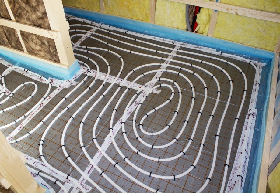 Das Rohrsystem einer Fußbodenheizung wird in einem Rohbau schneckenförmig verlegt. 