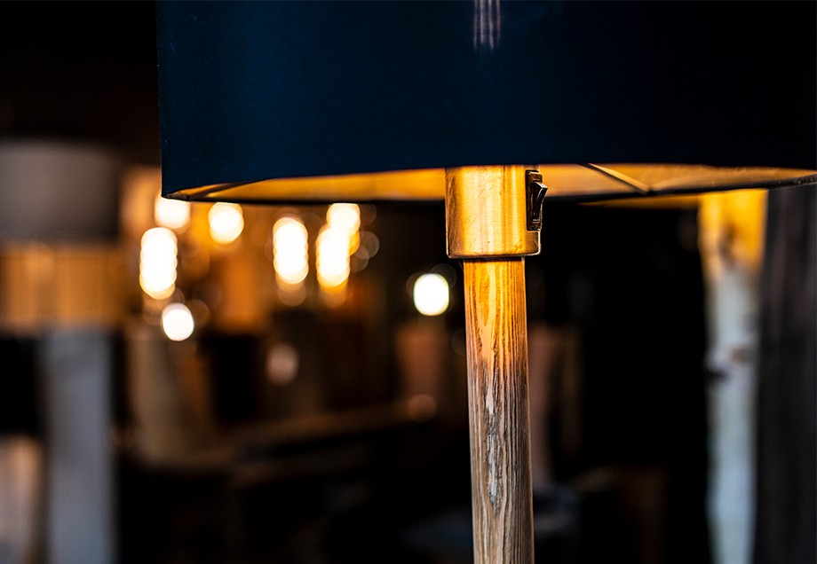 Im warmen Licht der Lampe fällt der Blick auf den Lampenfuß aus Holz.